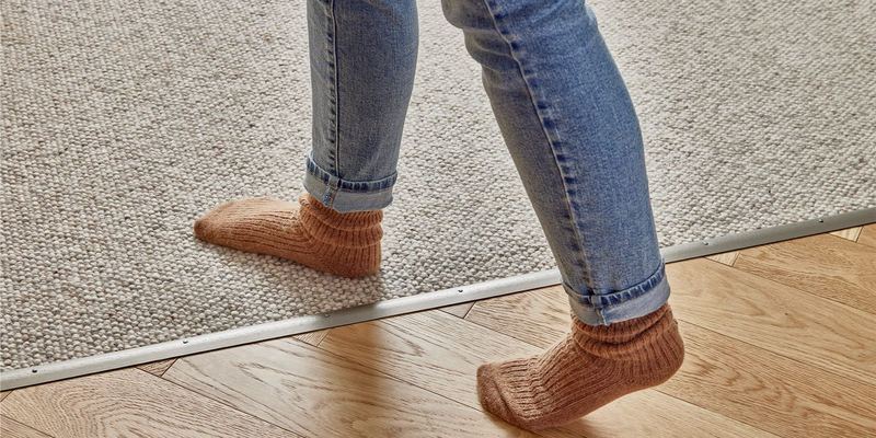 Feet stepping from a timber floor onto carpet across a neat trim
